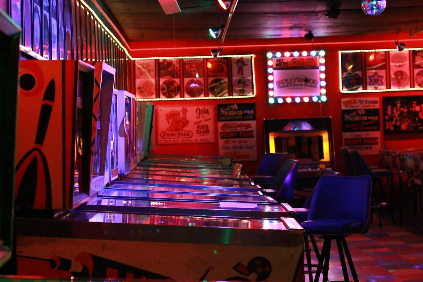 Fila di coloratissime macchine da flipper all'interno di una sala giochi retrò.
